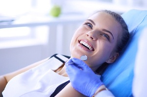A young woman smiling up at her dentist in preparation to receive pain-free dentistry in Agawam