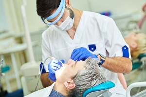 A male patient undergoing dental work after receiving painless local anesthesia