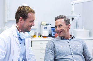 A male dentist talking to a male patient about his upcoming procedure