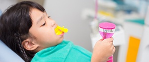 a child sitting in a dental chair holding a timer