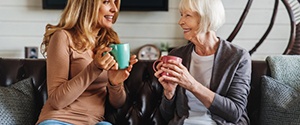 two women smiling and talking on a couch