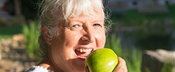 Woman eating an apple with dental implants in Agawam