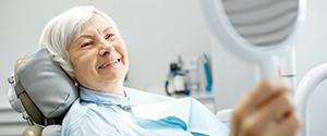 a patient looking at their implant dentures in the mirror