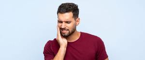 Man wearing burgundy t-shirt, experiencing mouth pain