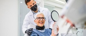 Senior dental patient admiring her teeth in mirror