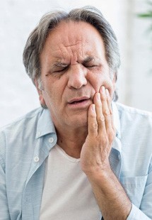 man holding cheek due to jaw pain near Feeding Hills