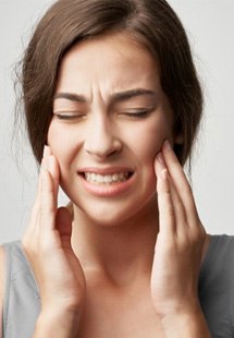 a woman holding her cheek due to tooth pain