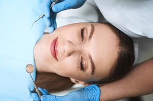 A young female lying back in a dentist’s chair and appearing calm before her treatment