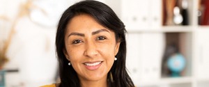 a smiling person standing in front of a bookshelf