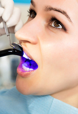 Dentist hardening woman’s filling with UV light