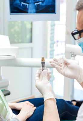 Dentist showing sample implant to patient