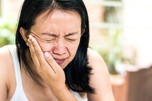 A woman holding her cheek in pain