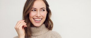 Woman with white teeth smiling in beige sweater