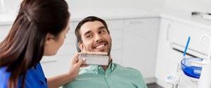 Dental assistant assessing color of smiling patient's teeth 