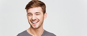Man in grey smiling after teeth whitening
