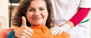 Woman in dental chair giving thumbs up