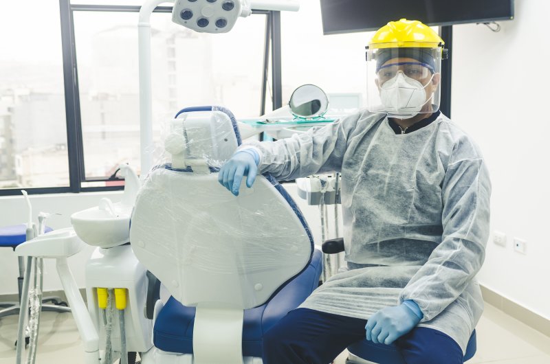 a dentist wearing personal protective equipment and preparing to see a patient 