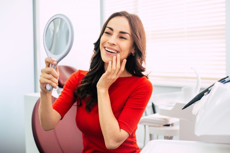 Smiling woman looking into hand mirror