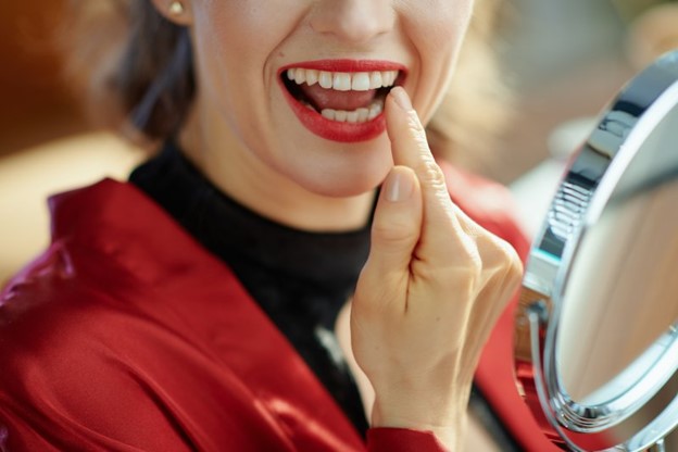 Woman inspecting her teeth after receiving teeth whitening.