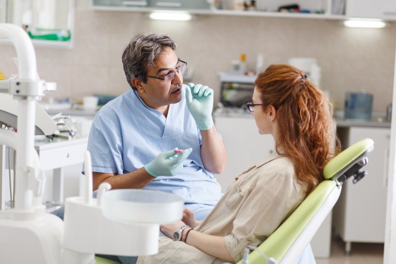 Senior male dentist in the dental office talking with a female patient