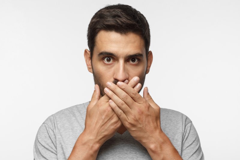 a man covering mouth from a cosmetic dentist in Agawam