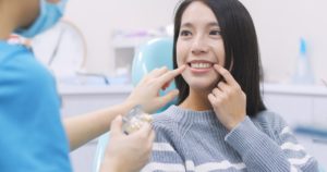 Woman in dentist’s chair pointing to her tooth