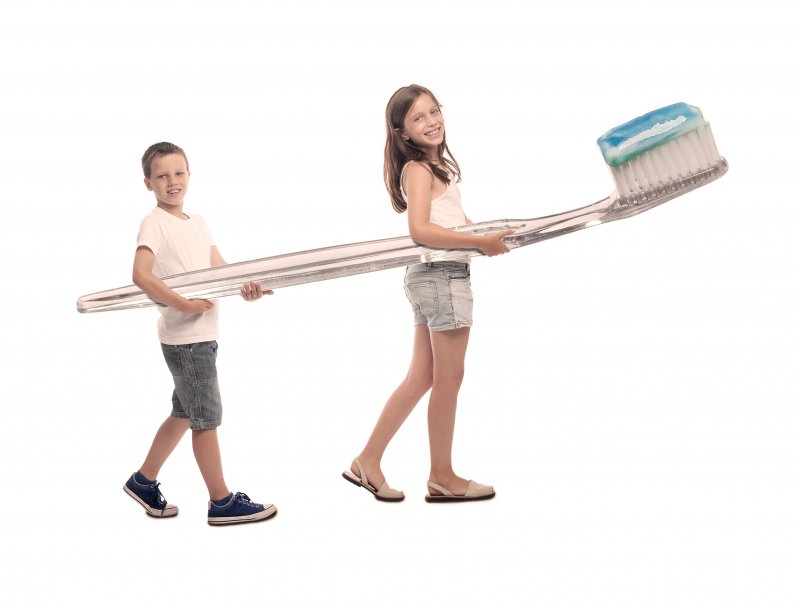 two kids carrying a massive toothbrush