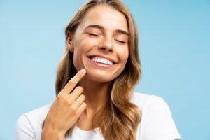 Woman smiling while pointing at her veneers